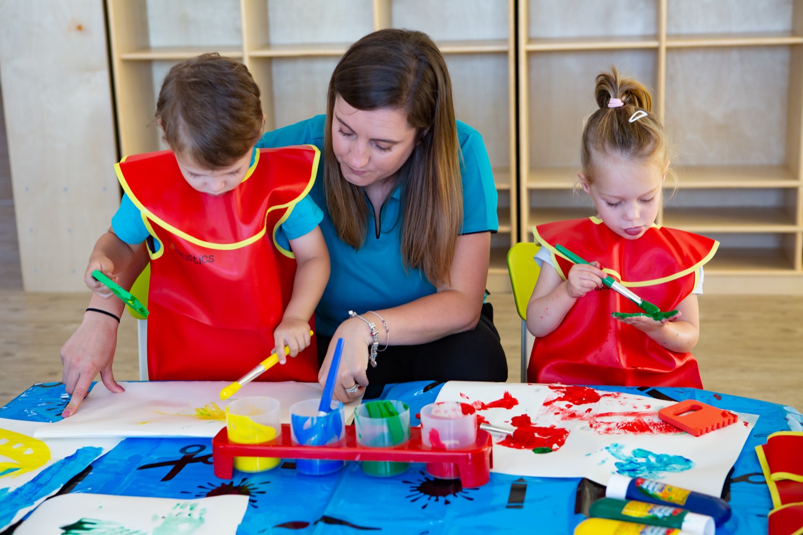 An educator sitting on the floor alongside a child during an activity